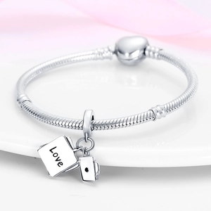 Close-up of silver snake chain bracelet with heart clasp and love book charm on tray
