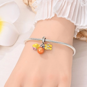 Close-up of silver snake chain bracelet with summer themed enamel charms on a wrist