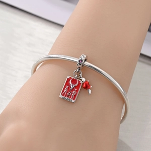 Detailed view of The Devil tarot charm and red winged heart on silver beaded bracelet
