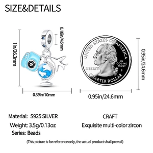 Macro shot of silver travel charms with camera and globe, shown with a coin for scale