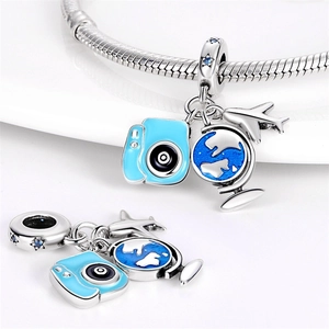 Detailed view of silver travel charms with blue enamel camera, globe, and plane on a ring