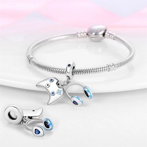 Détails macro de breloques manette et casque en argent sur un bracelet maille serpent