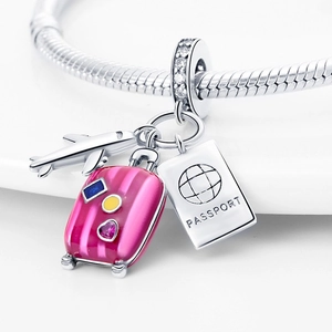 Macro shot of silver airplane, pink suitcase and passport charms on a snake chain