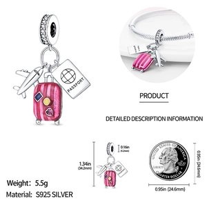 Detail of travel charm with suitcase and airplane next to a coin for size comparison
