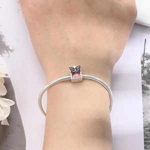Close-up of pink enamel perfume bottle charm with butterfly on silver snake chain