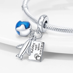 Macro detail of silver travel charms with blue globe, airplane, and envelope on snake chain