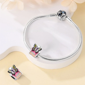 Detail of silver charm bracelet featuring pink perfume bottle pendants and purple butterflies