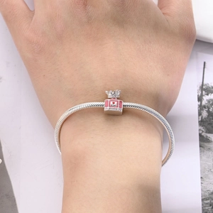 Silver snake chain bracelet featuring pink enamel perfume bottle pendant with crown detail
