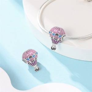 Detailed macro view of silver hot air balloon charm with pink enamel and blue stones