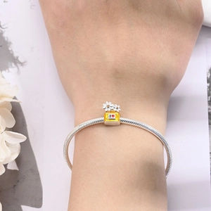 Detailed view of silver snake chain bracelet with yellow enamel perfume bottle pendant