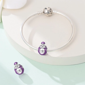 Detail of silver perfume bottle charm with purple enamel and Dream Boldly engraving