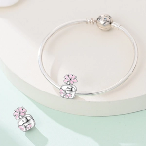Detailed close-up of perfume bottle charms with pink enamel flowers on a silver bracelet