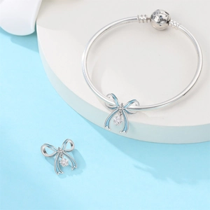 Detailed shot of bow charms with blue enamel and We belong together engraved silver bracelet