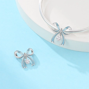 Blue enamel bow charm with zircon star detail for silver bracelets shown on display stand