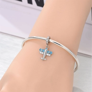Close-up of a silver airplane charm with blue enamel and zircons on a delicate bracelet