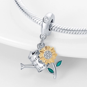 Detailed close-up of a sunflower and watering can charm with green enamel and tiny crystals