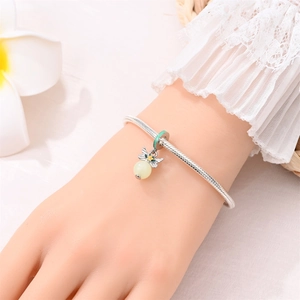 Detailed close-up of a silver insect pendant with green bead and yellow flower on a bracelet