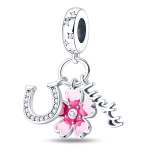Macro shot of silver lucky charm featuring a pink enamel sakura and a horseshoe with crystals