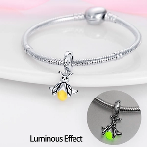 Macro detail of luminous firefly pendant charm and silver snake chain with glow effect