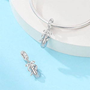 Macro shot of silver ballet slipper charms with light blue enamel and dancing engraving
