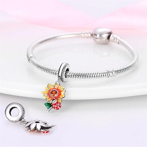 Macro view of sunflower and ladybug charm with orange zircon on silver snake chain