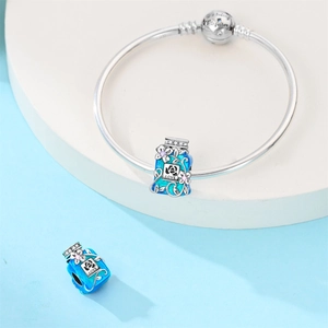 Macro shot of blue enamel charm with LOVE text and engraved silver bangle buckle