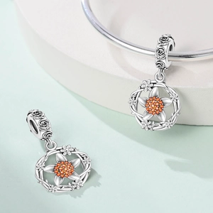 Detail of floral charm bead with orange crystals and rose engraved bail on a bracelet