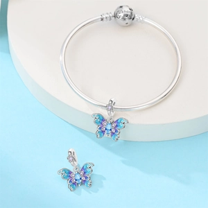 Detalle del dije de mariposa en esmalte azul y cierre de pulsera grabado en plata
