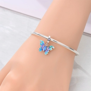 Primer plano de dije de mariposa plateado con gema azul y esmalte en brazalete elegante
