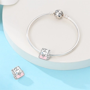 Macro shot of silver school bag charm with pink enamel and Back to School engraving