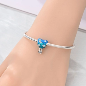 Detail of silver bracelet with heart-shaped blue gradient enamel charm and star pattern