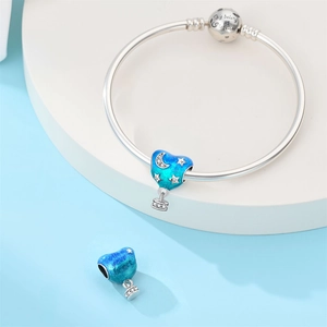 Macro shot of silver charm bracelet with blue enamel hot air balloon and heart engraving