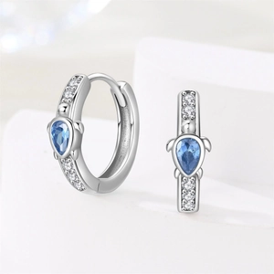 Macro detail of silver turtle hoop earrings with blue zircon drop and micro pavé stones