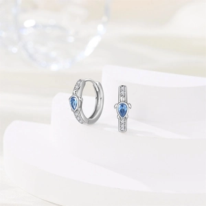 Close-up of silver dolphin earrings with teardrop blue crystal and pavé zircon stones