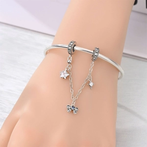 Detalle de pulsera de plata con cierre de corazón, estrellas y colgante de mariposa azul