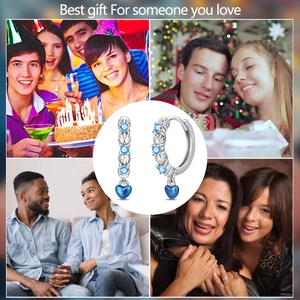 Detailed view of silver hoop earrings with blue stones and heart charms in gift setting