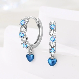 Detail of silver hoop earrings featuring blue crystals, sea shells and heart-shaped charms