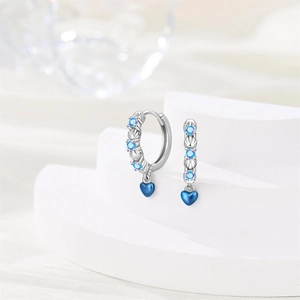 Detailed close-up of silver earrings with blue stones and heart-shaped shell pendants