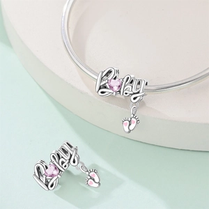 Detalle de charm plateado con texto Baby, circonita de corazón rosa y colgante de pie