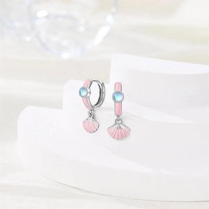 Close-up of silver-tone shell earrings with pink enamel and iridescent stones