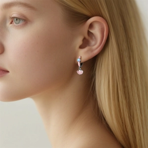 Detail of mermaid shell hoop earring with pink enamel and light blue gemstone on model