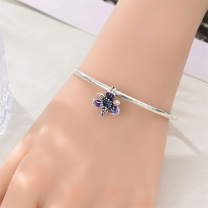 Detail of silver bangle with a purple enamel flower charm and colorful stone accents