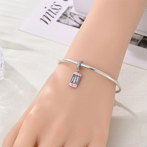 Detalle de pulsera plateada con colgante de consola rosa y texto de Game Over