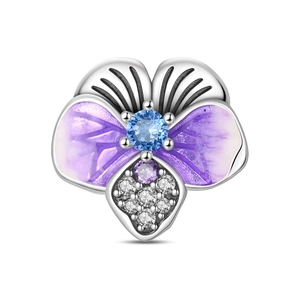 Macro shot of a purple enamel iris flower charm with blue gemstone and silver plating