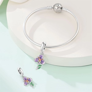Macro view of silver bracelet with purple enamel pansy charm and engraved clasp detail
