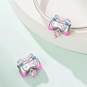 Detalle macro del dije de mando de juego en plata con esmalte rosa y gema de corazón