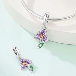 Detailed view of a purple flower charm with orange gem on a silver beaded bracelet