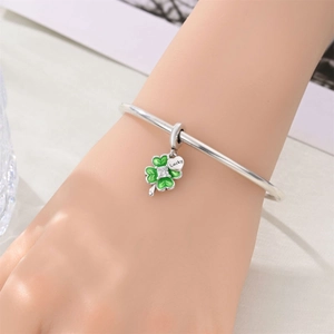 Macro detail of silver four-leaf clover charm with green enamel and Lucky heart tag