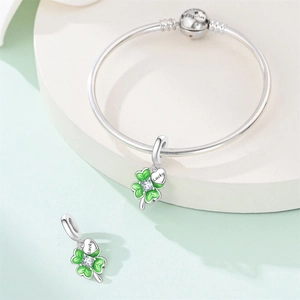 Detailed macro of silver charm bracelet with green enamel clover and Lucky engraving