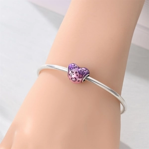 Dettaglio di un bracciale in argento con ciondolo a cuore sfumato viola e incisione Love